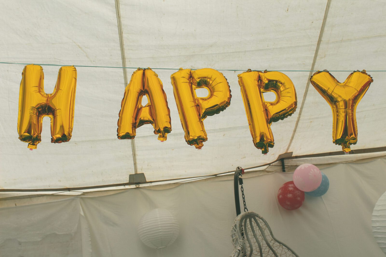 Gold helium balloons spelling 'Happy' as festive indoor decoration.